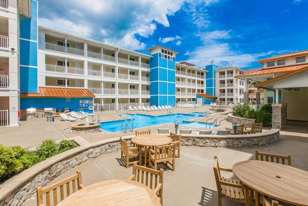 An outdoor pool courtyard is surrounded by seating and a multi-story building.