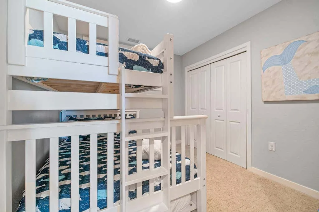 Un dormitorio con literas blancas y ropa de cama azul estampada.