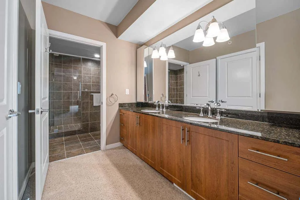 Un tocador de baño con una encimera larga y una zona de ducha con azulejos.
