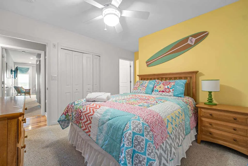 Un dormitorio con una colcha de colores y una cómoda de madera.