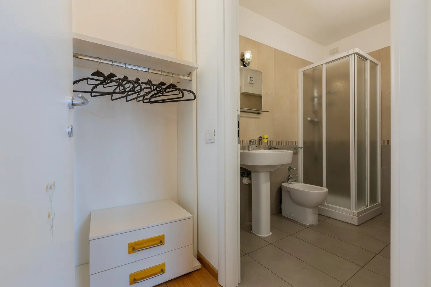 A bathroom with a shower, sink, and toilet is visible beside a small clothes closet.