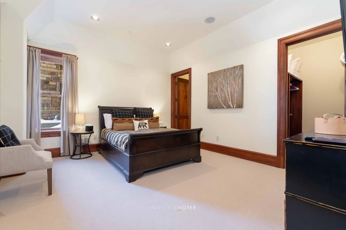 A bedroom with a bed, a window, and a framed artwork on the wall.