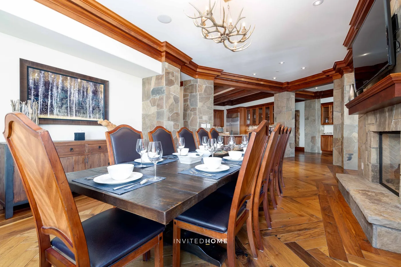 A formal dining room with a long table set beneath a chandelier.