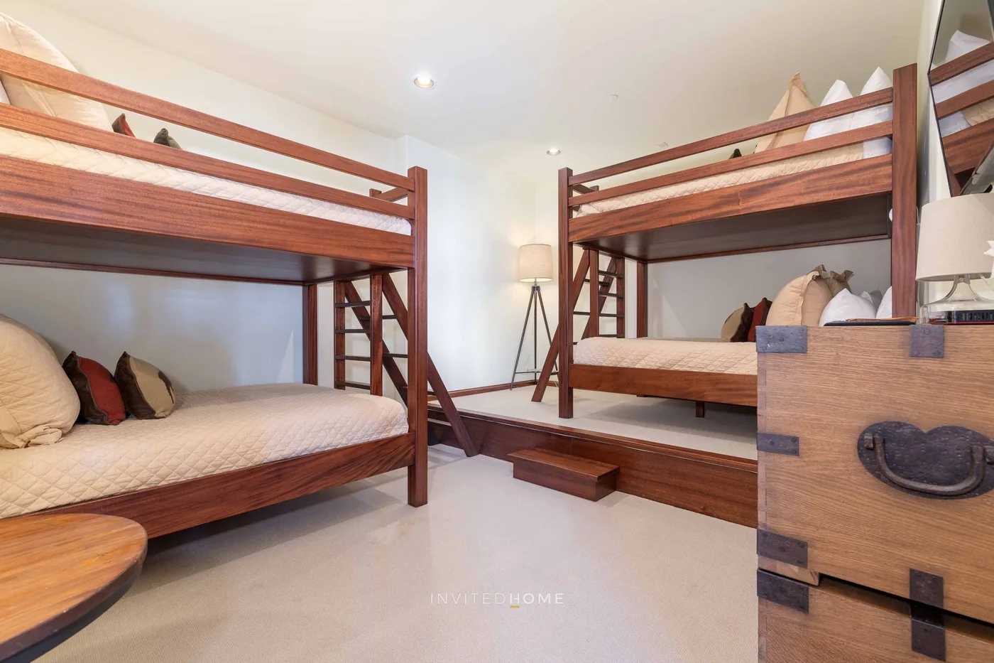 A bedroom with wooden bunk beds and a chest of drawers.