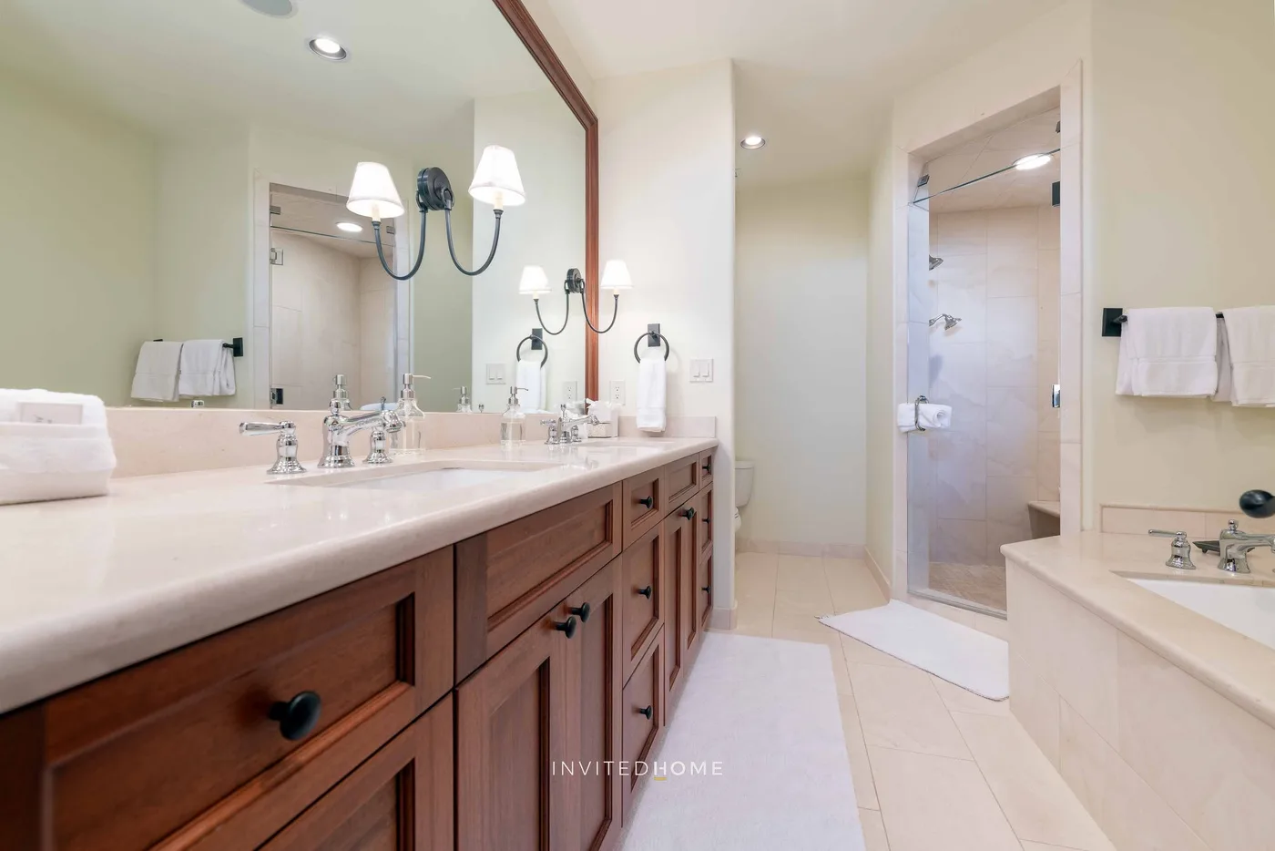 A bathroom with a long vanity, wall mirror, and glass shower.