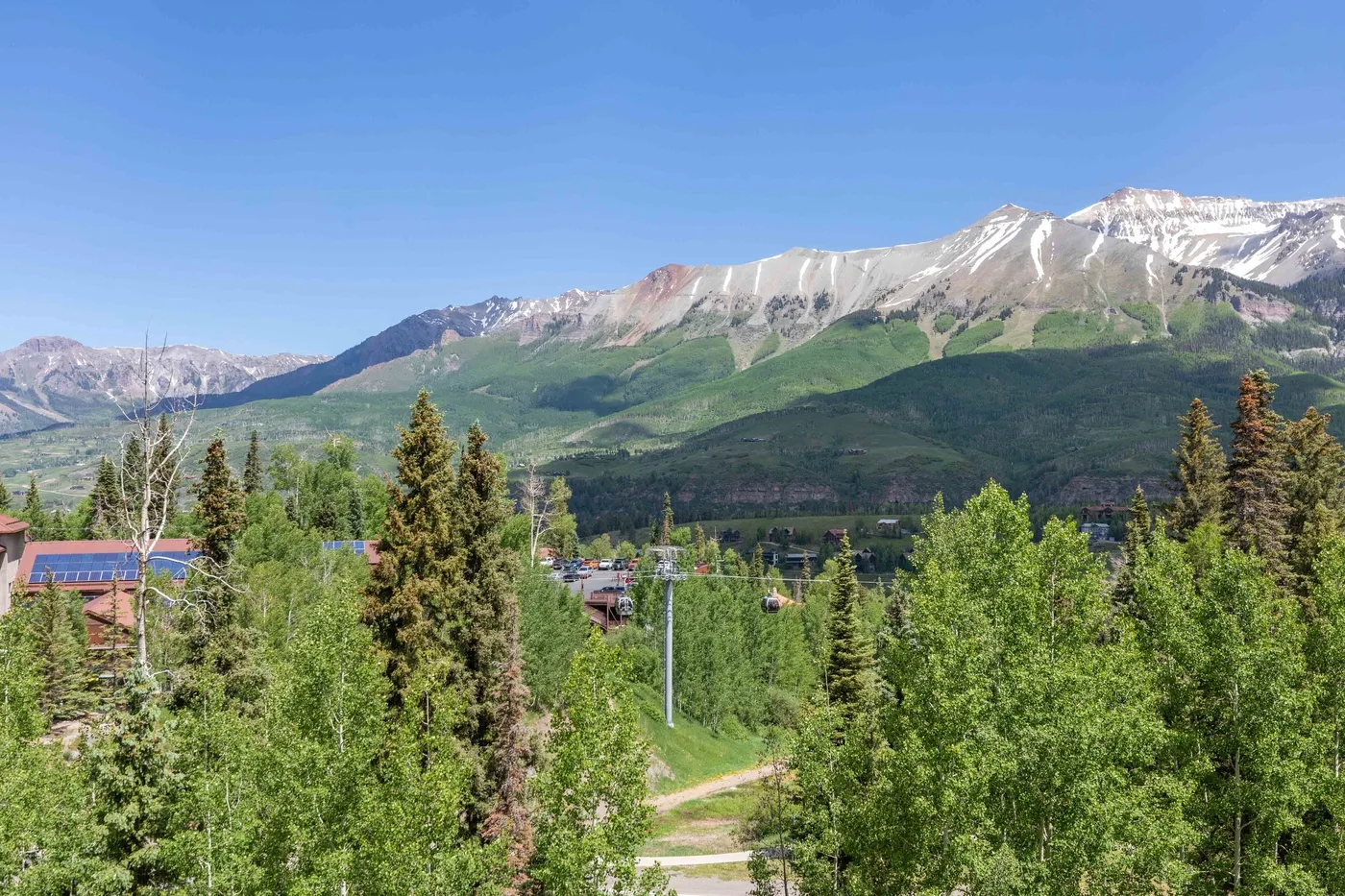 A mountain landscape rises above a forested valley under a clear blue sky.