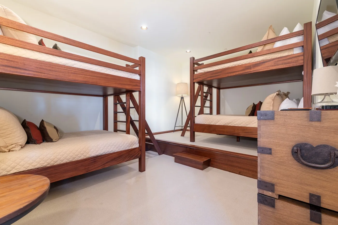 A bedroom with two wooden bunk beds and a small chest.