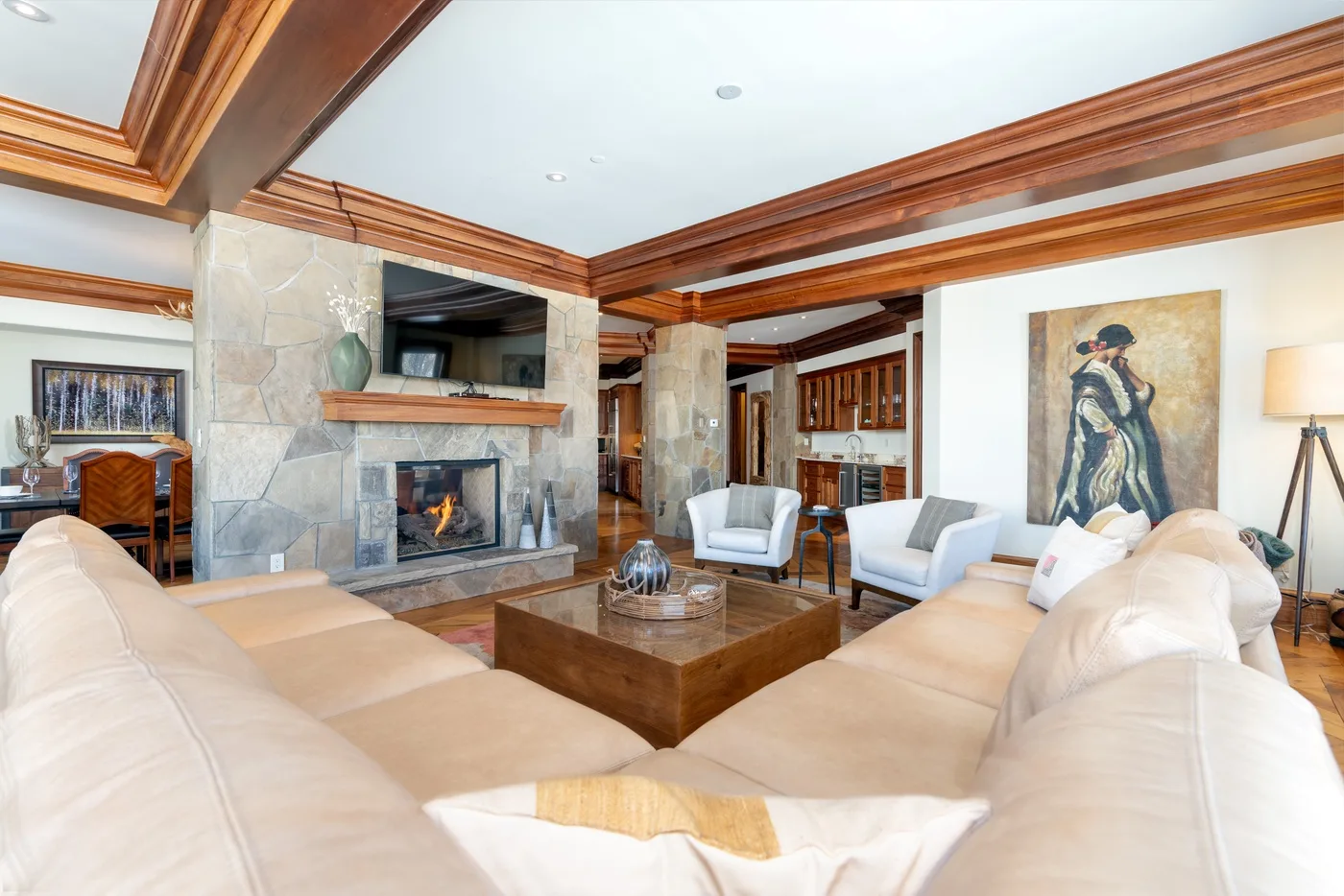 Living room with light-colored seating arranged around a wooden coffee table and fireplace.