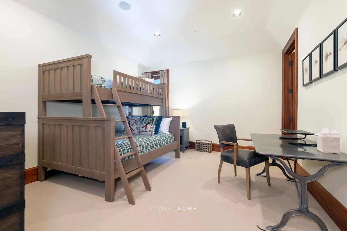 A bedroom with a wooden bunk bed, a desk, and a chair.