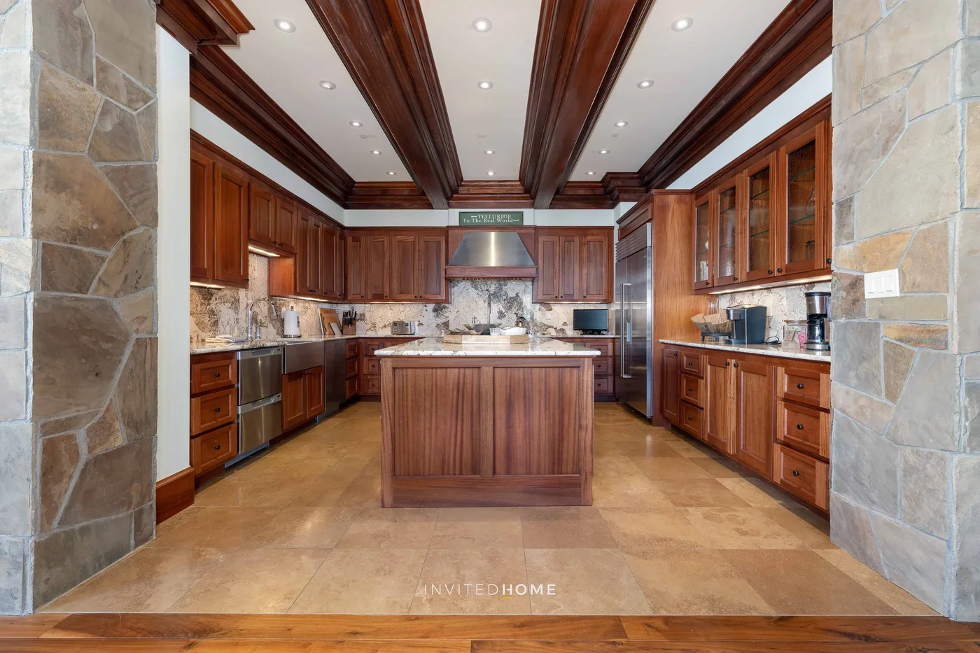 A kitchen with wooden cabinets, stone counters, and a central island.