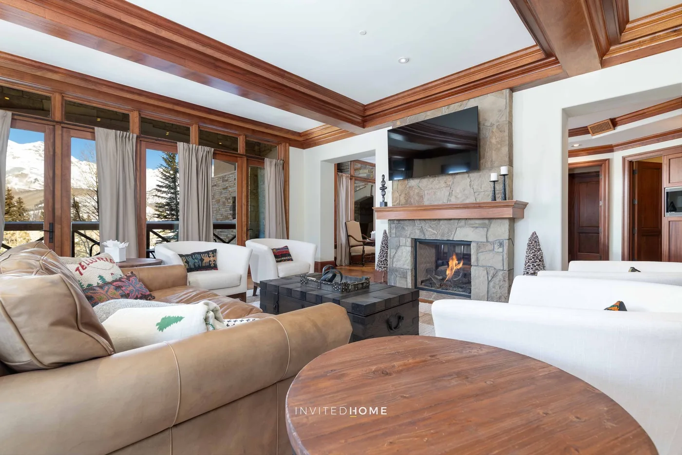 A living room with seating arranged around a stone fireplace and television.