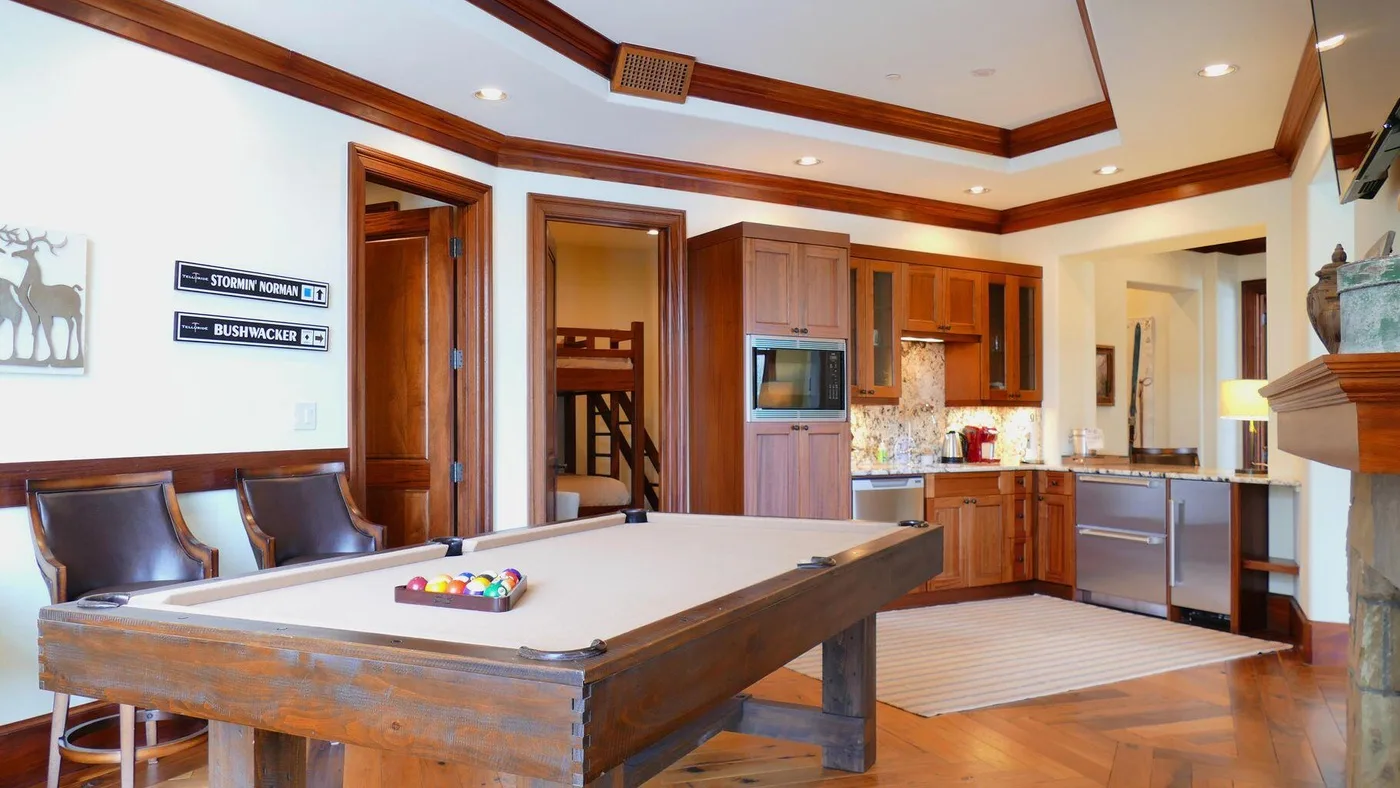 A game room with a pool table beside a kitchen.