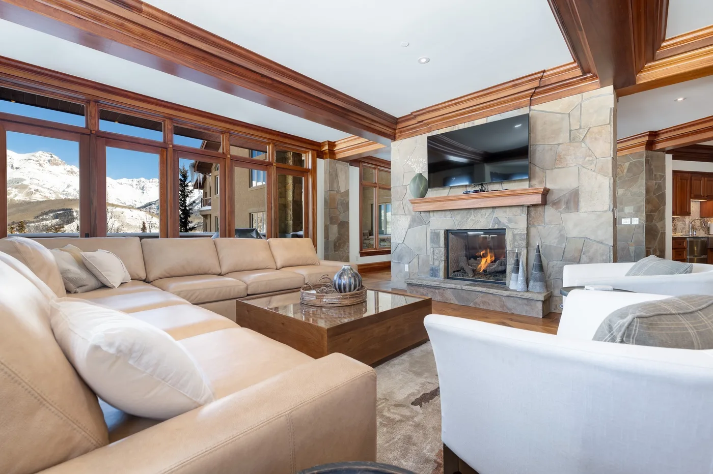 A living room with seating arranged around a stone fireplace and television.