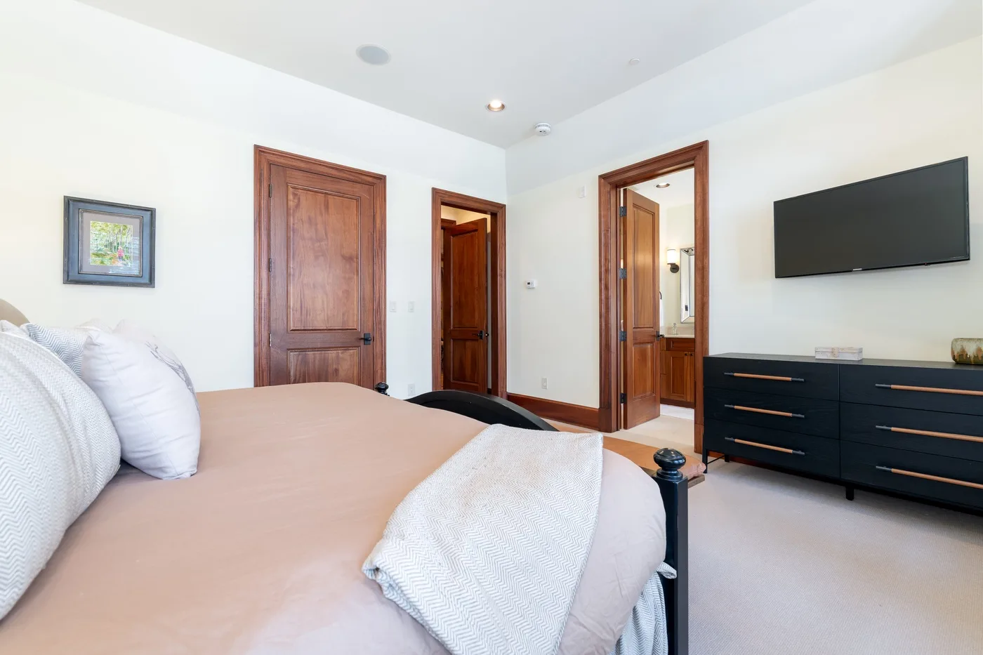 Bedroom with a bed, dark dresser, and wall-mounted television.