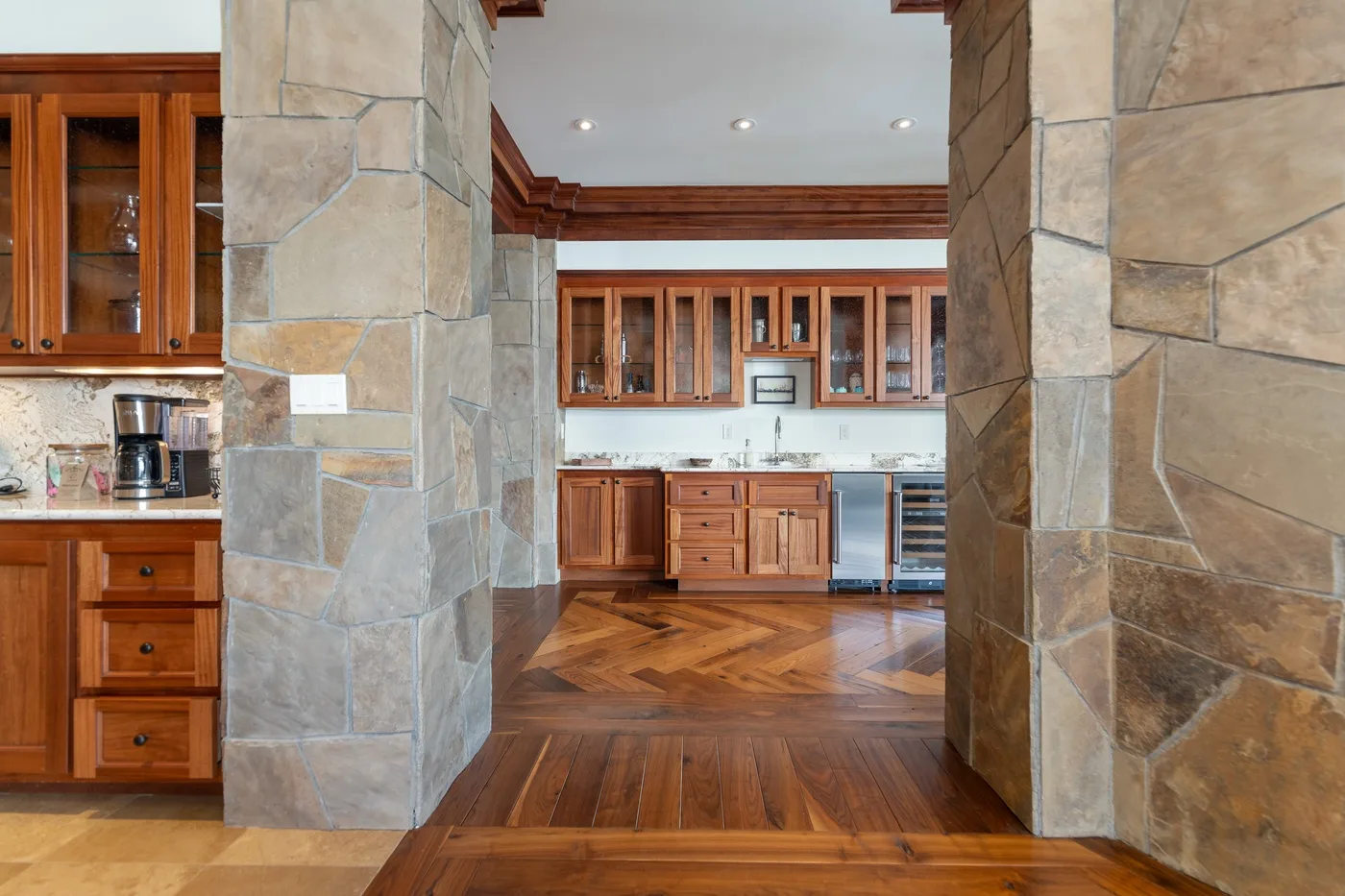 A kitchen with wooden cabinets and a stone-framed opening.