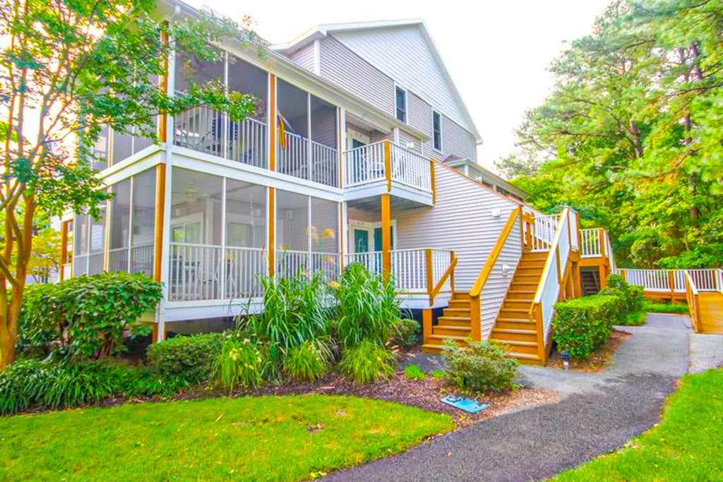 A multi-level building with exterior balconies and a staircase beside a paved path.