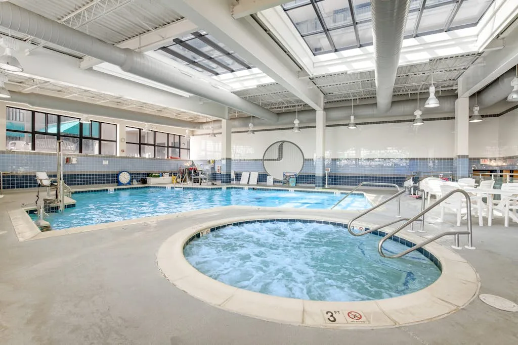 An indoor swimming pool with a bubbling circular spa in the foreground.
