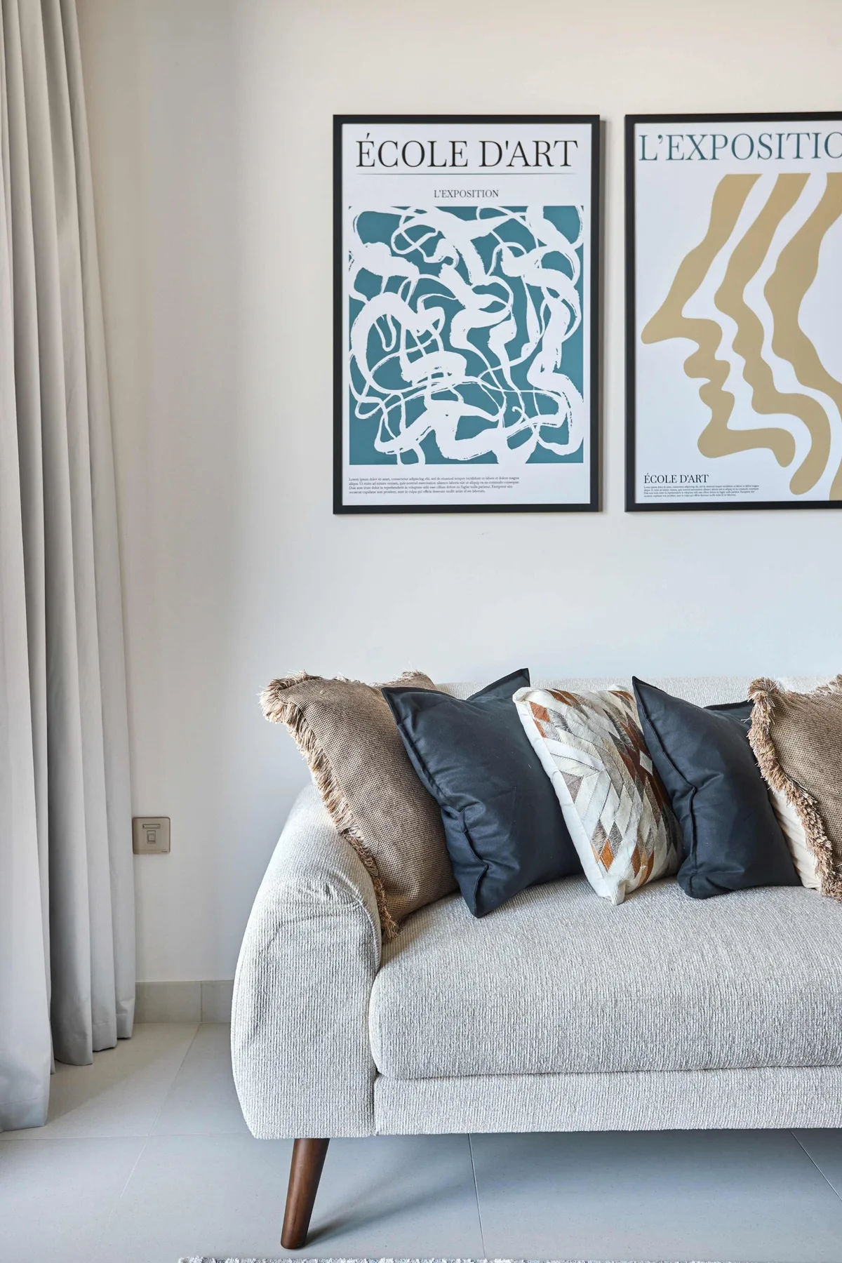 A living room with a light-colored sofa beneath framed artwork.
