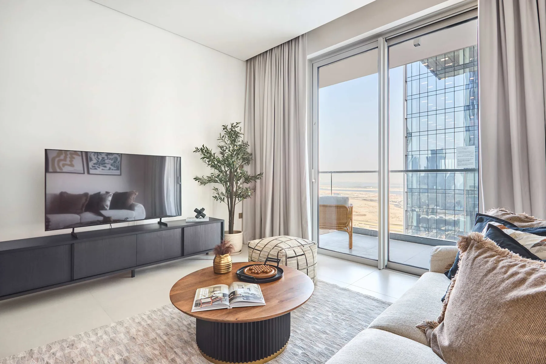 A bright living room with seating, a television, and large glass doors.