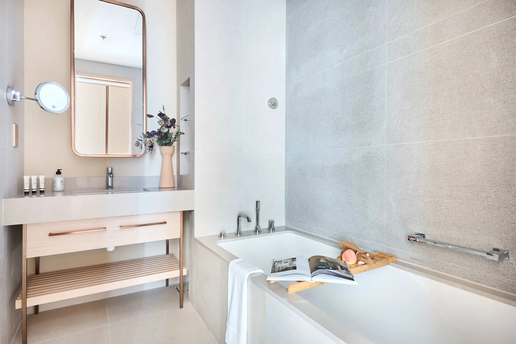 A bright bathroom with a bathtub, vanity, and an open book.