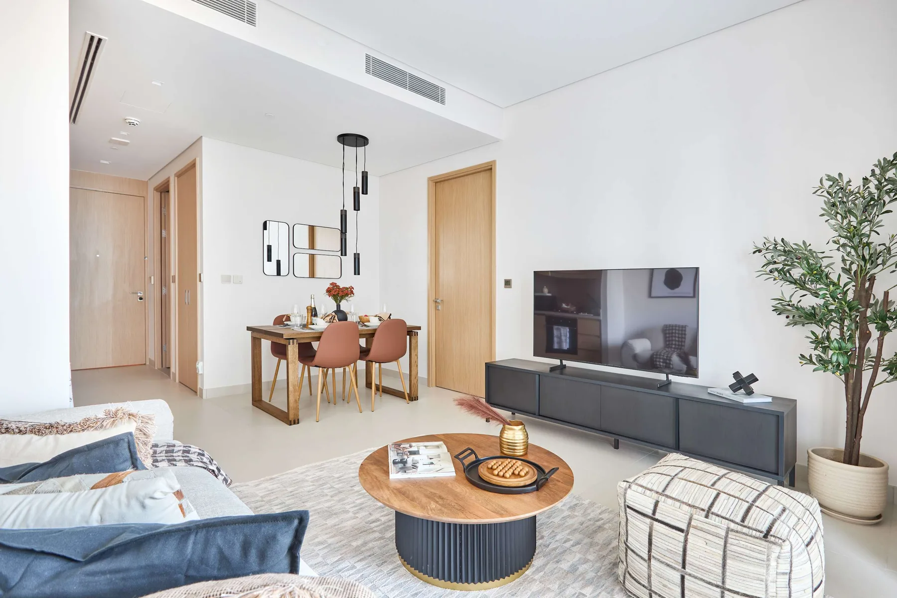 A bright living room with a dining table, television, and seating area.