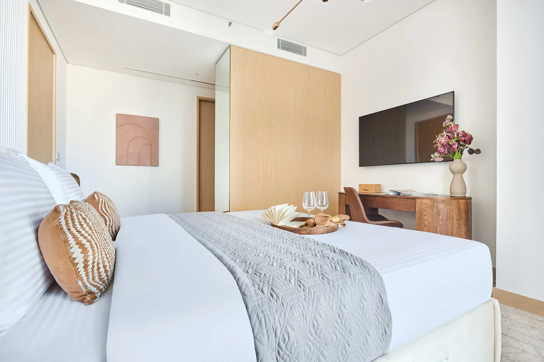 A bedroom with a neatly made bed and a wall-mounted television.