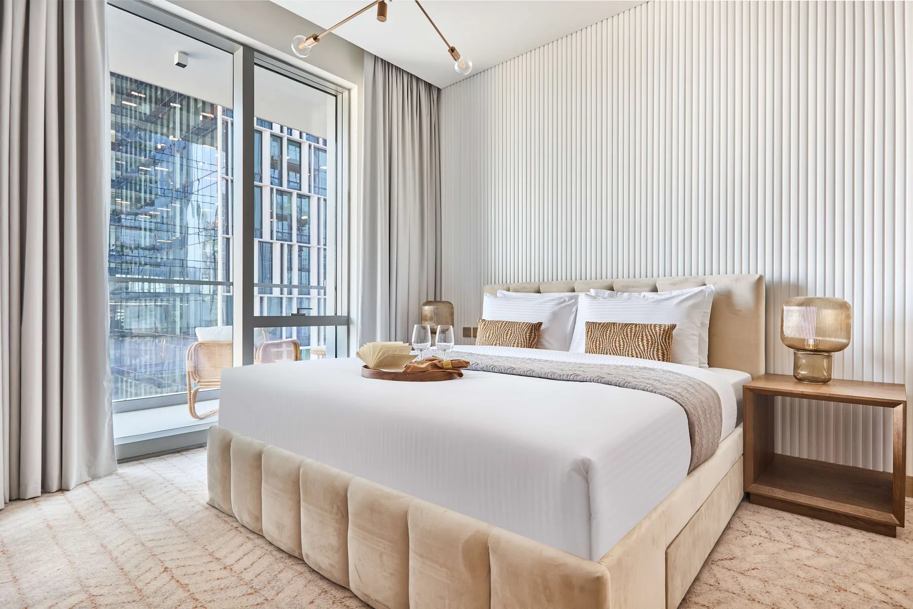 A bedroom with a large bed, bedside tables, and floor-to-ceiling windows.