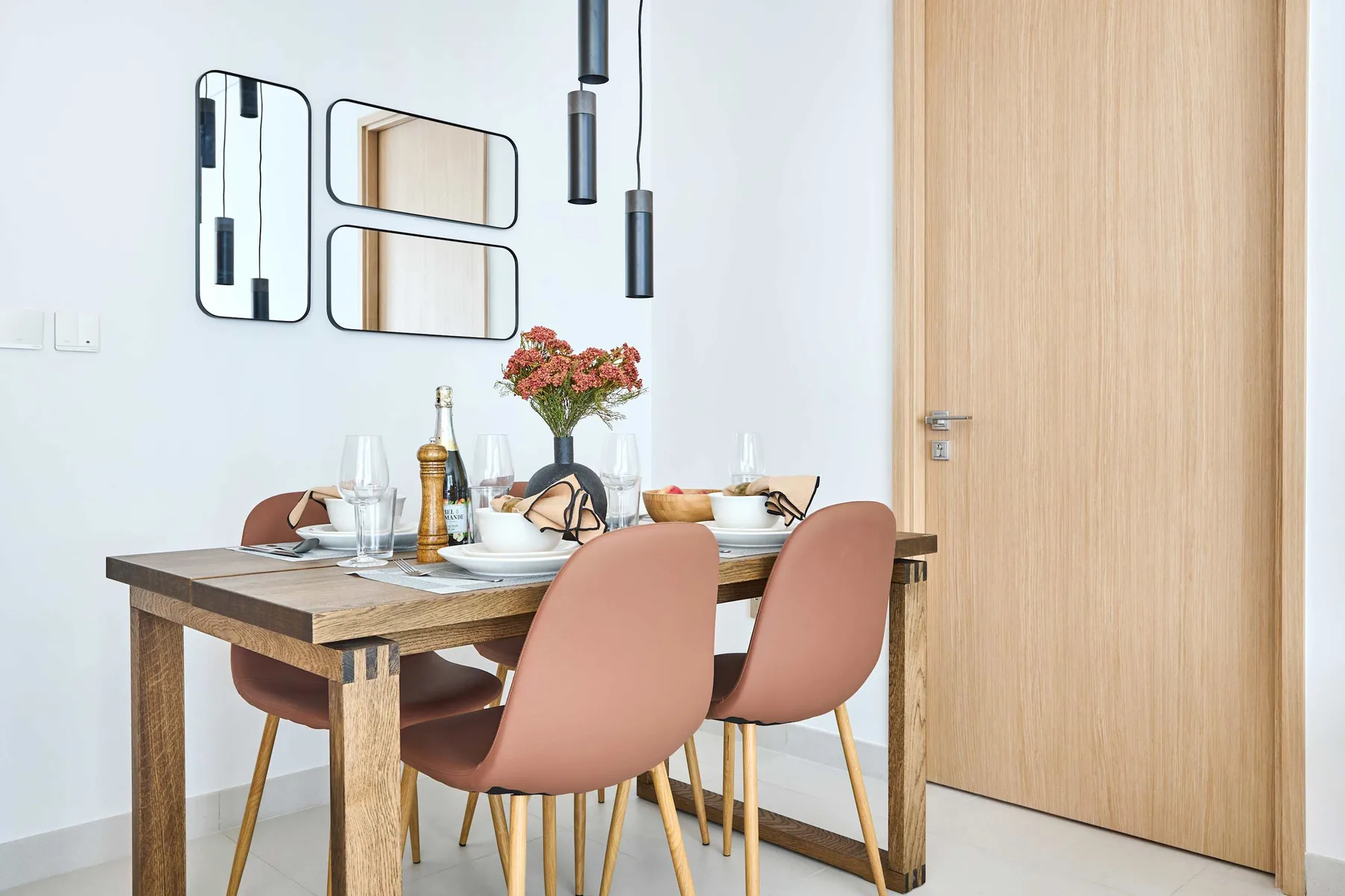 A dining area with a set table, pink seating, and flowers.