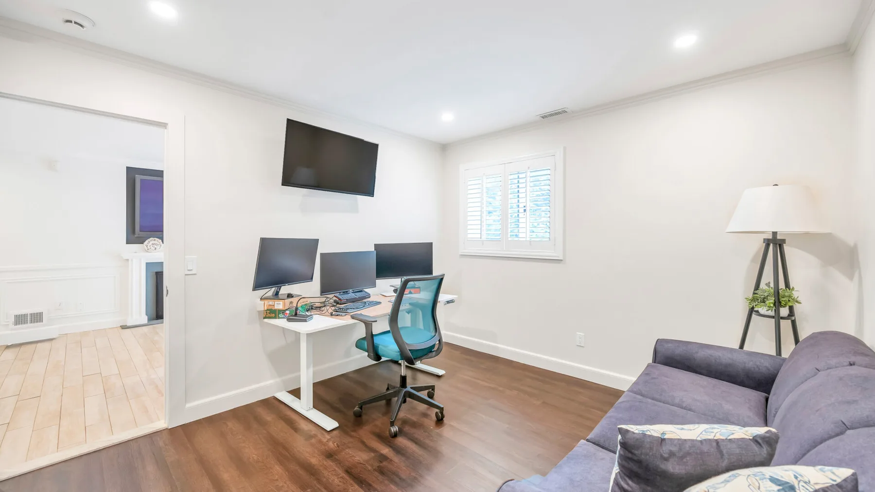 Una luminosa zona de trabajo y estar con escritorio, monitores y sofá.
