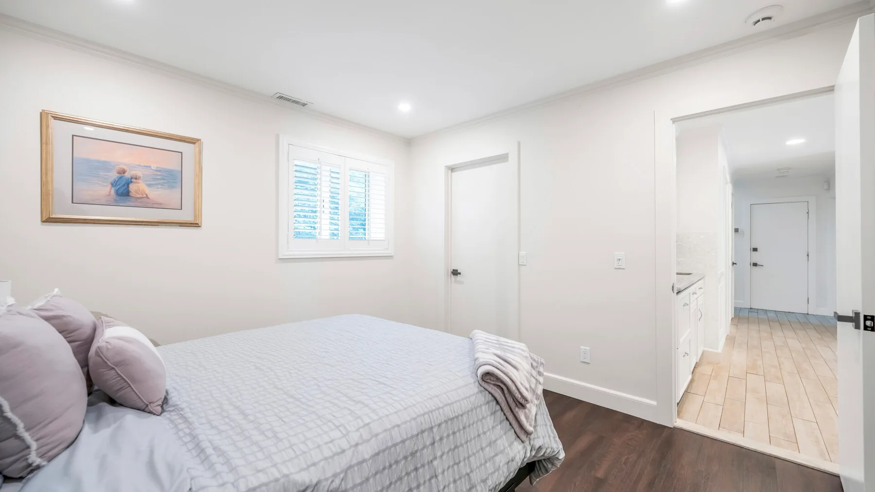 Un dormitorio con una cama bien arreglada y un cuadro en la pared.
