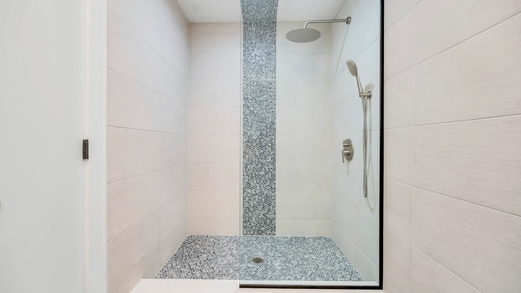 Una zona de ducha alicatada con rociador de lluvia y ducha de mano.