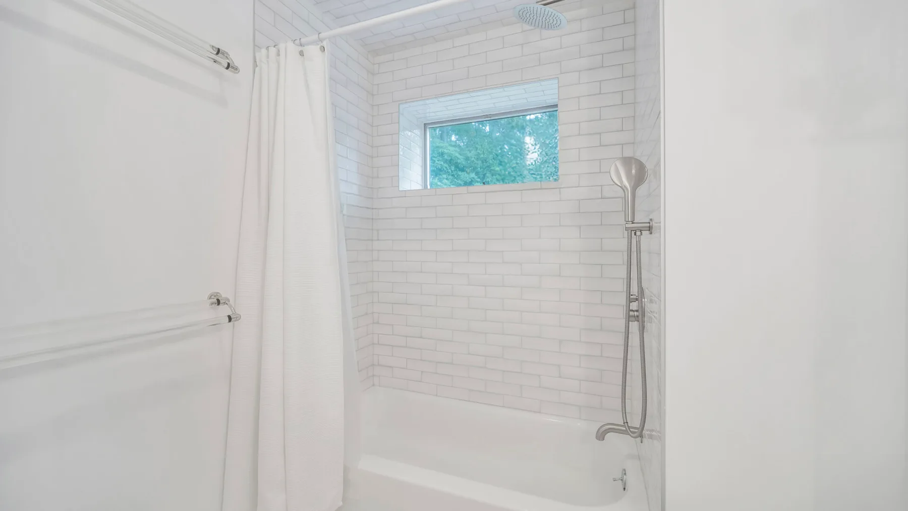 Un baño luminoso con azulejos, ducha y una ventana pequeña.