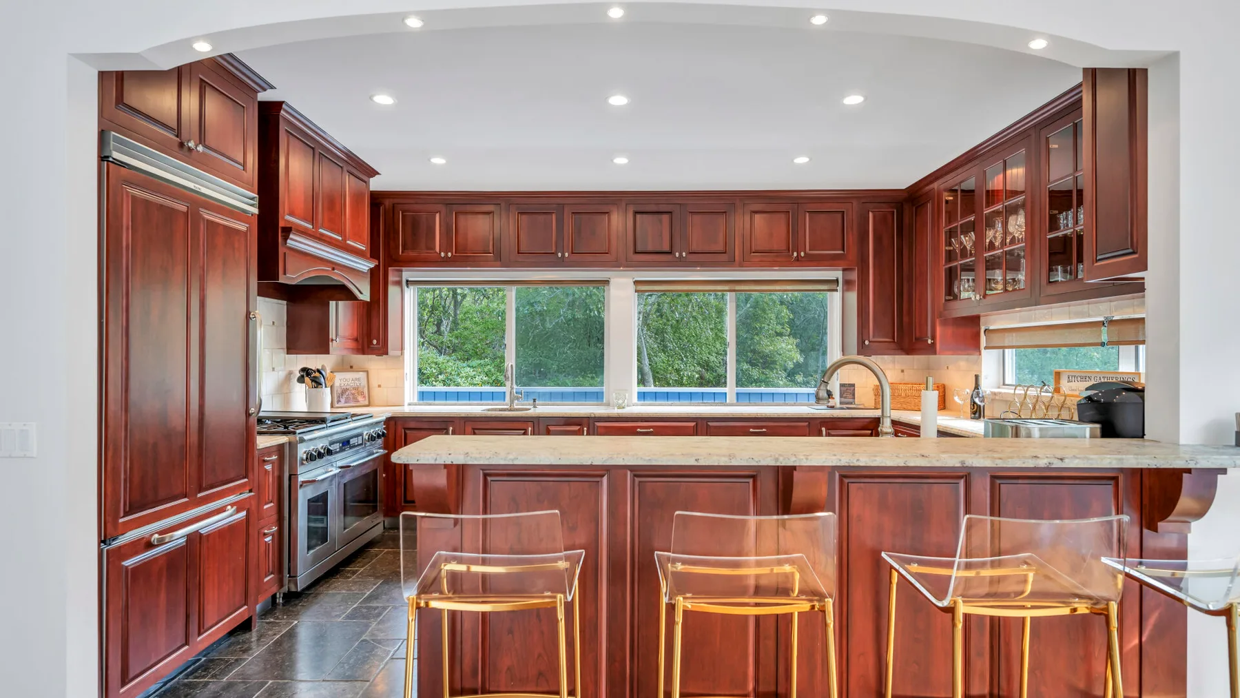 Una cocina amplia con gabinetes de madera oscura, una isla central y ventanas sobre el fregadero.
