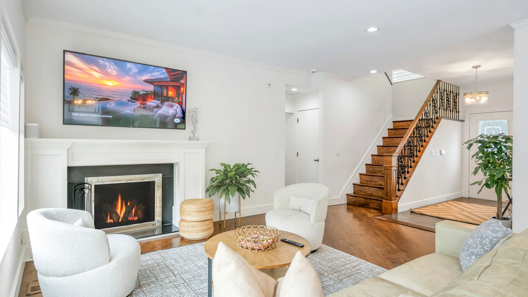 Una sala luminosa con chimenea, asientos y una escalera.