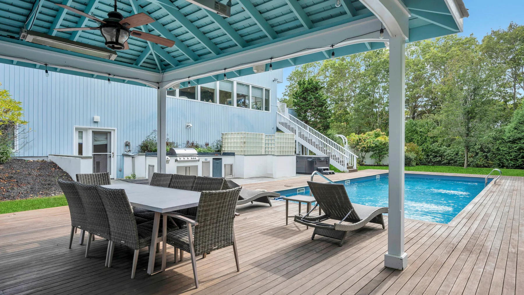 Una terraza exterior cubierta con asientos de comedor y una piscina.