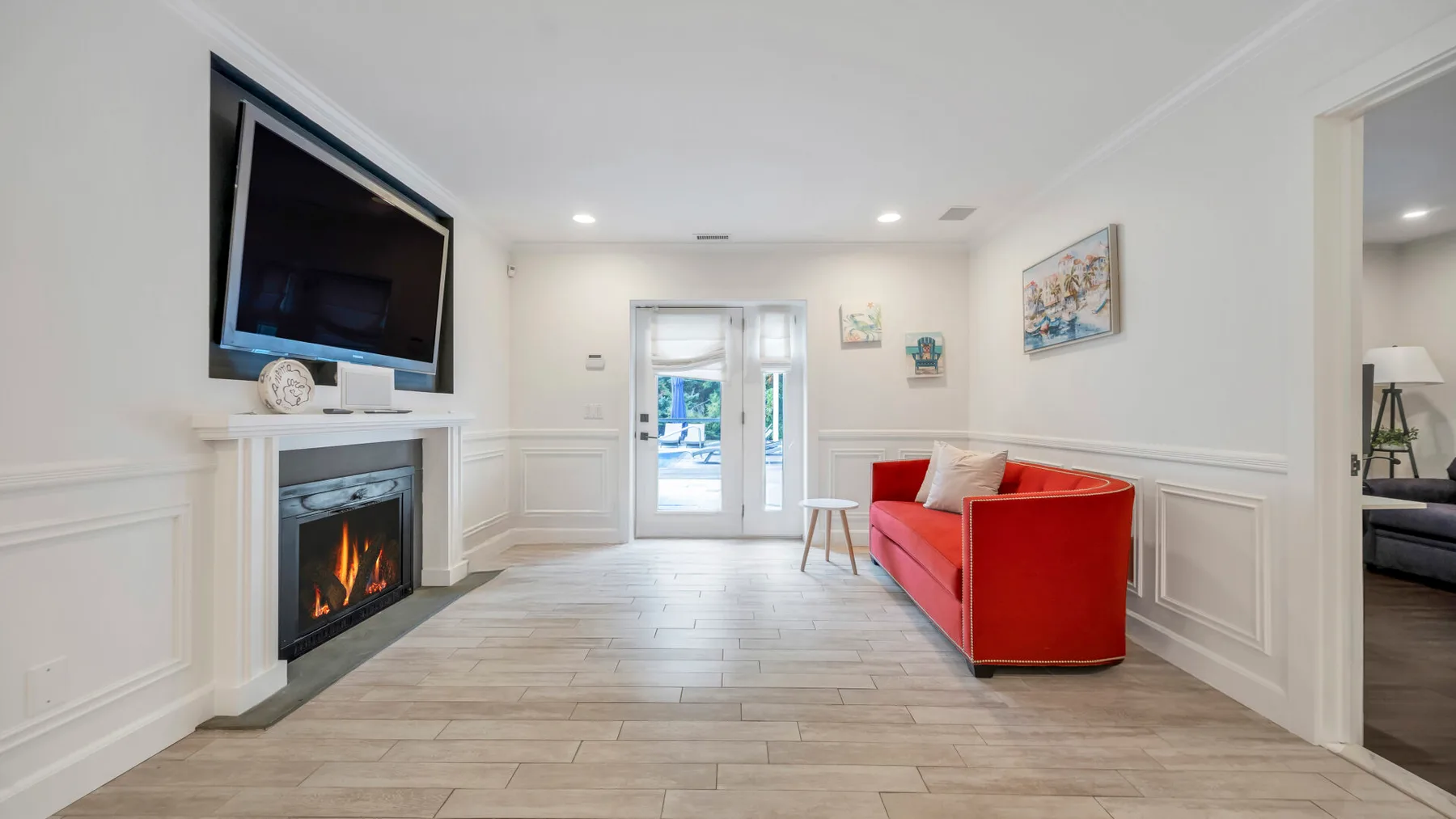 Una sala luminosa con un sofá rojo, chimenea y puertas de cristal.