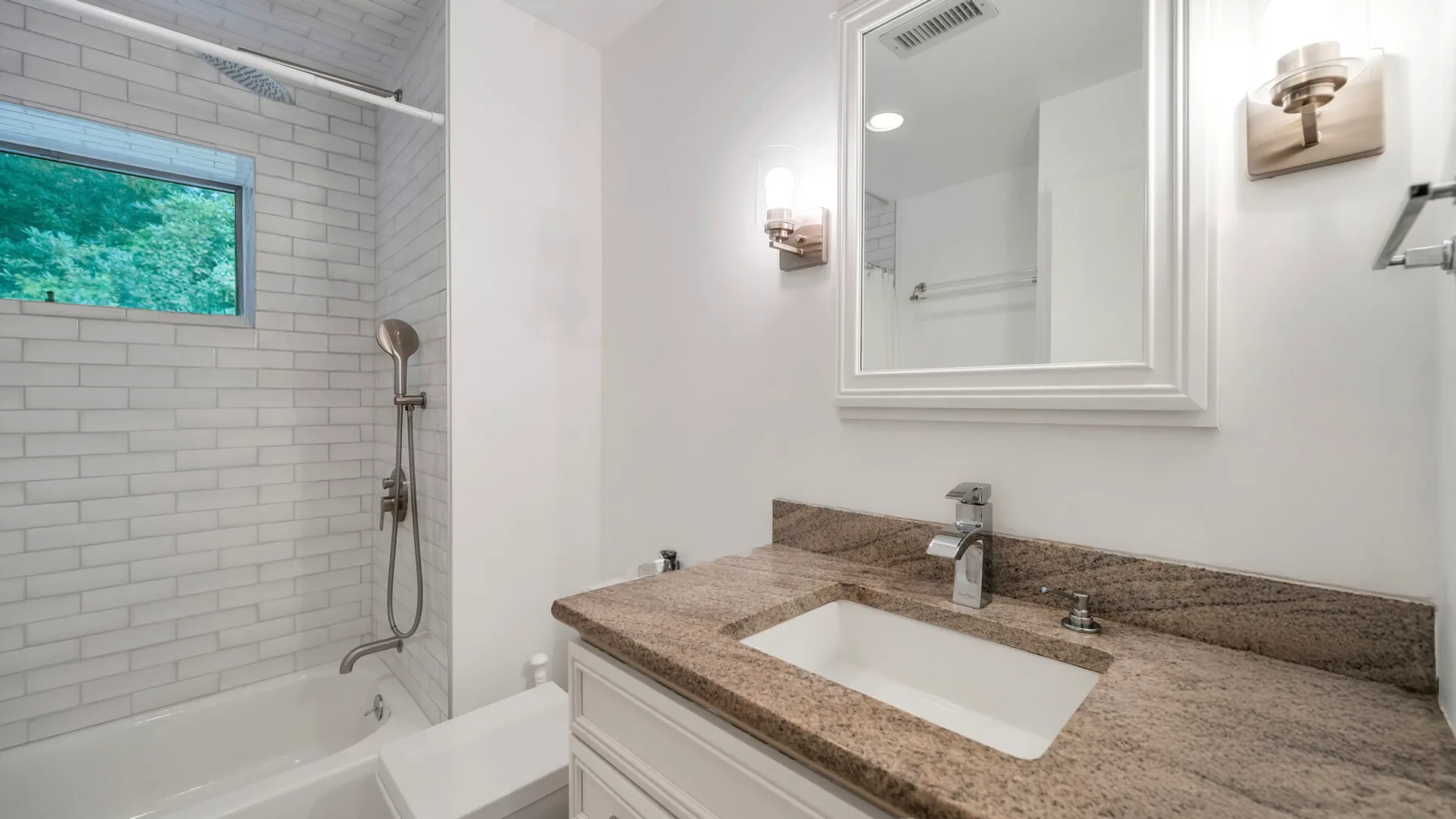 Un baño con lavabo, espejo y ducha sobre la bañera.