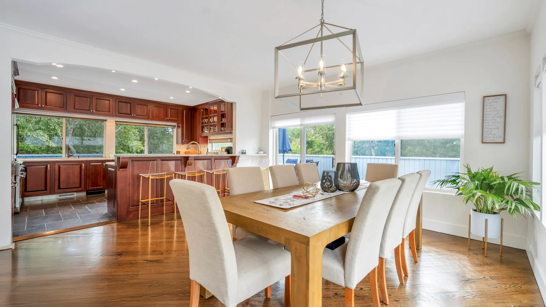 Comedor con una mesa de madera y asientos tapizados claros junto a la cocina.