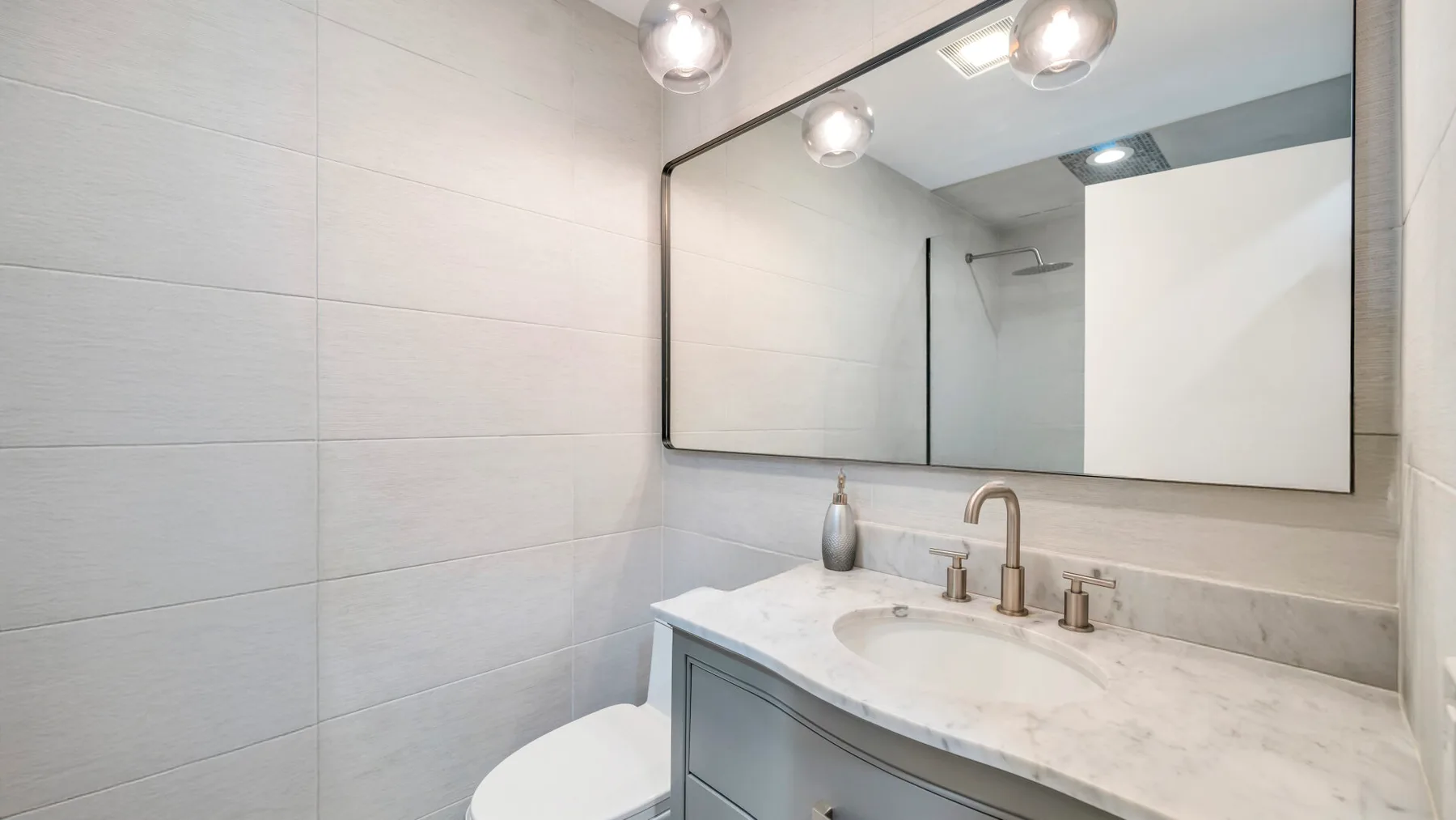 Un baño luminoso con un amplio espejo sobre un mueble con lavabo.