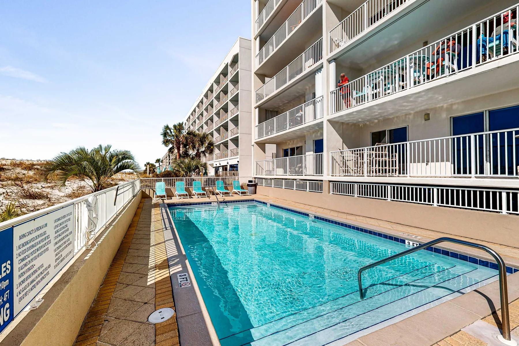 An outdoor swimming pool beside a multi-story building with balconies.