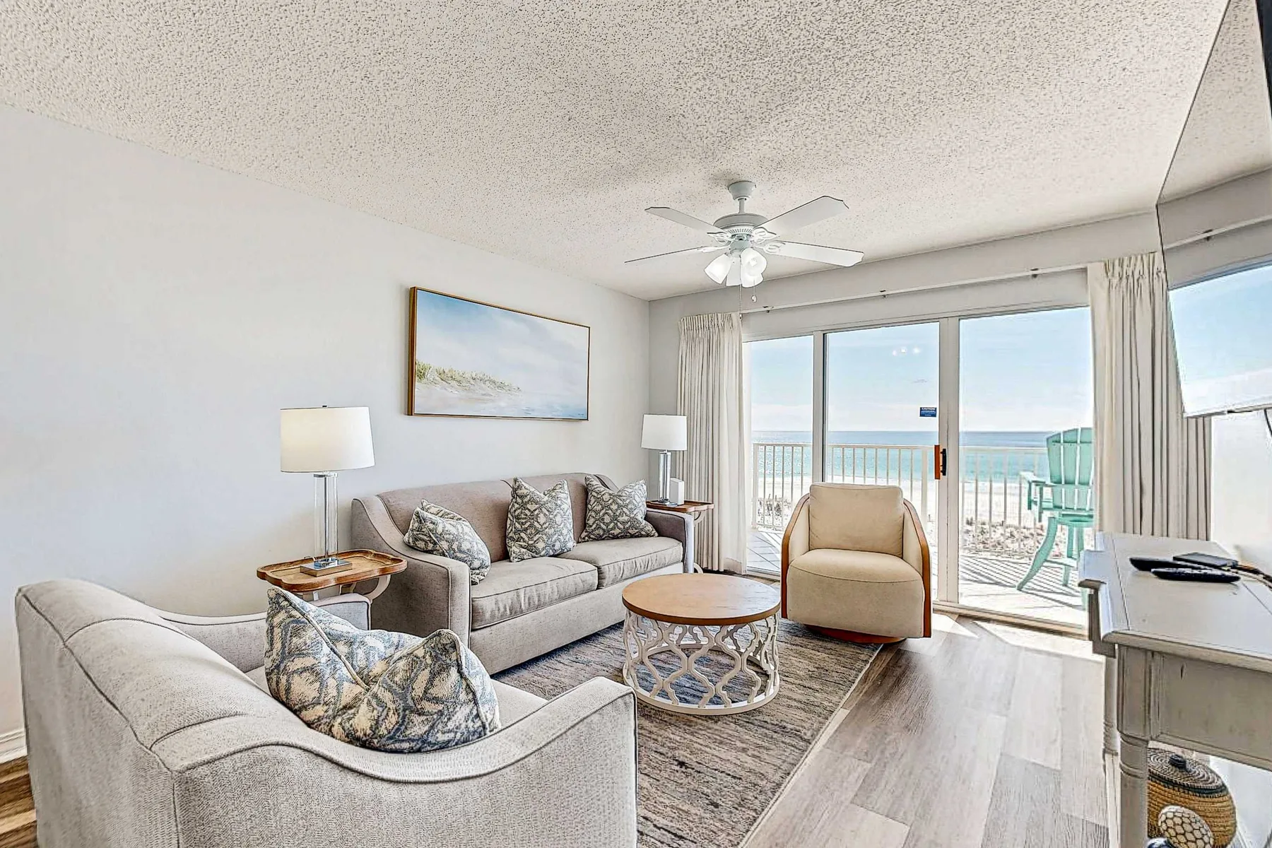 A bright living room opens onto a balcony with ocean views.