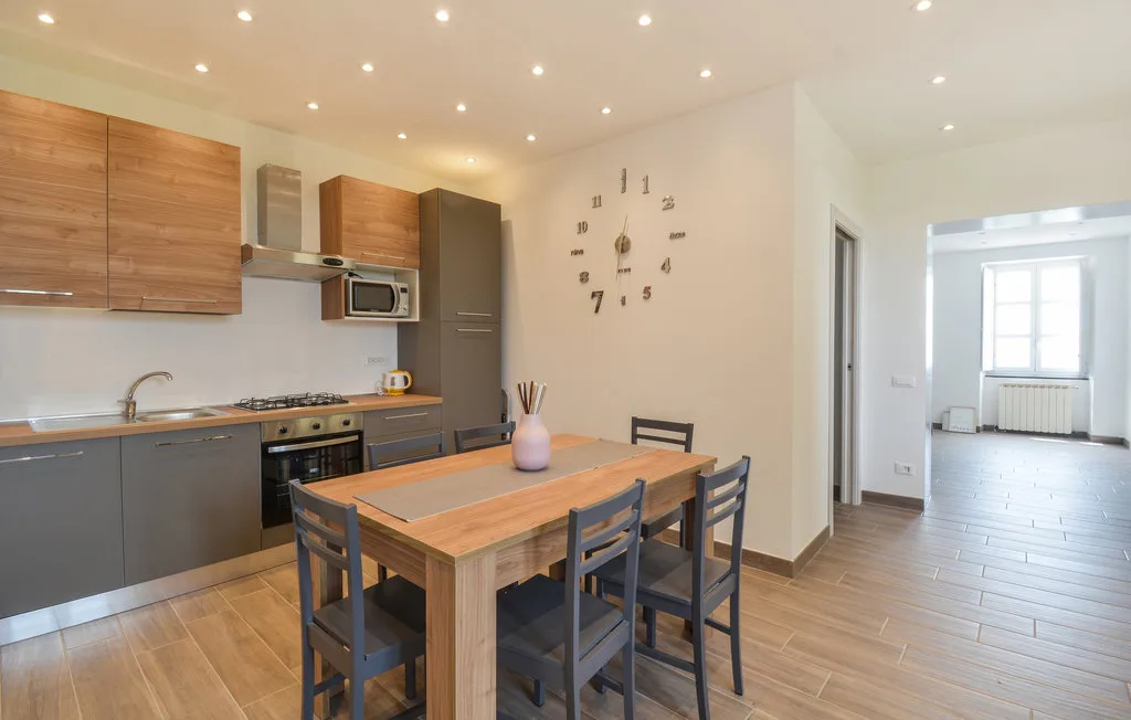 An open-plan kitchen and dining area with a wooden table and gray seating.