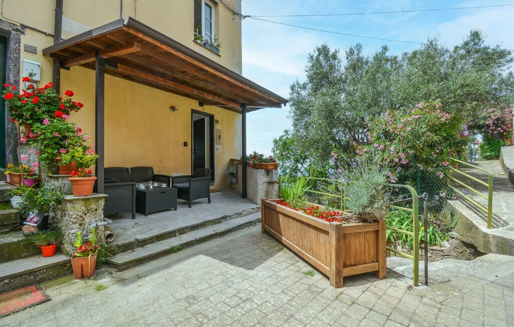 A covered patio with outdoor seating and a wooden planter beside the garden.