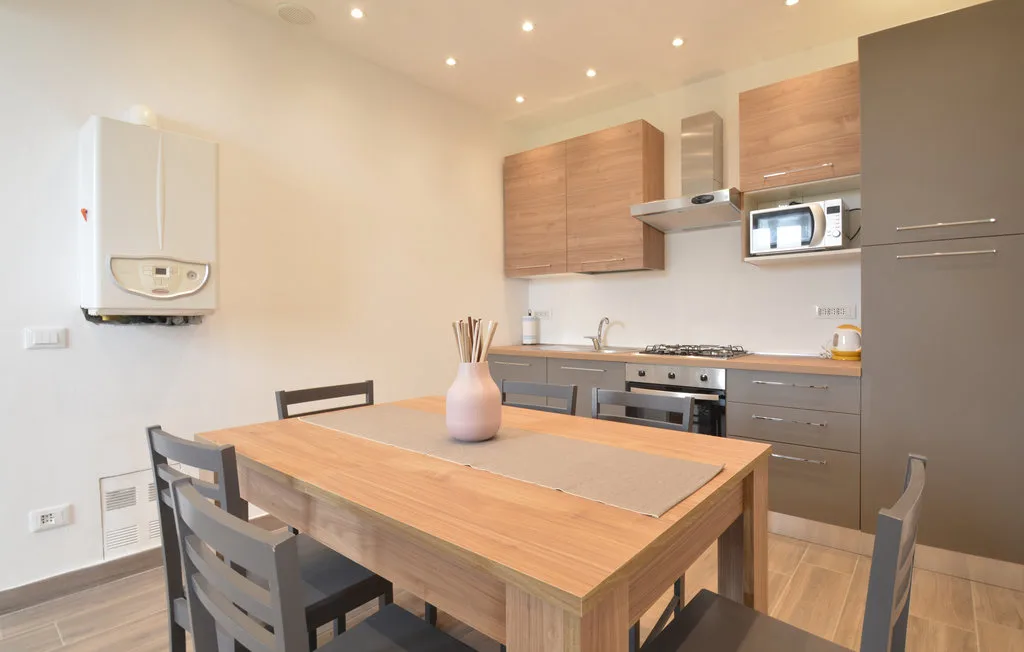 A dining table and chairs sit in a bright kitchen with wood cabinets.