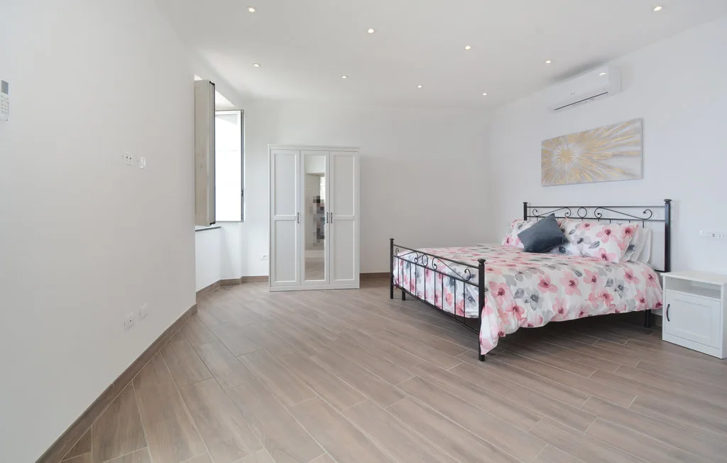 A bright bedroom with a metal bed and floral bedding.