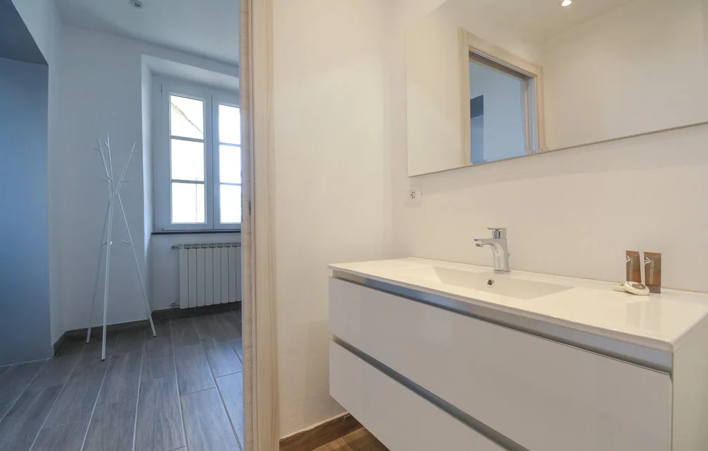A bathroom vanity with a sink and mirror opens onto a room with a window.