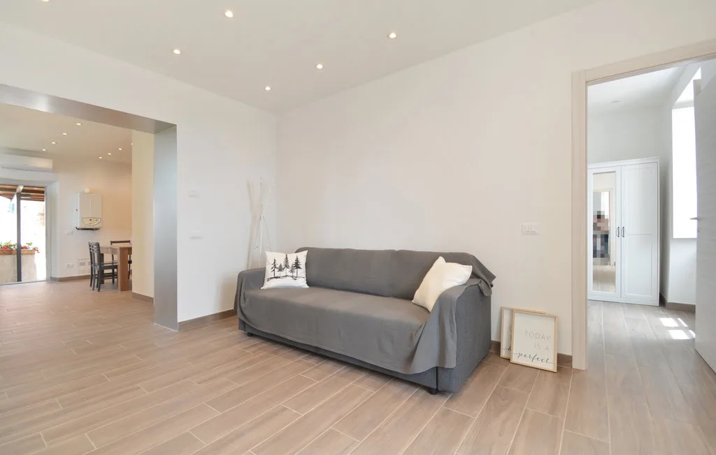 A bright living room with gray seating and open doorways.