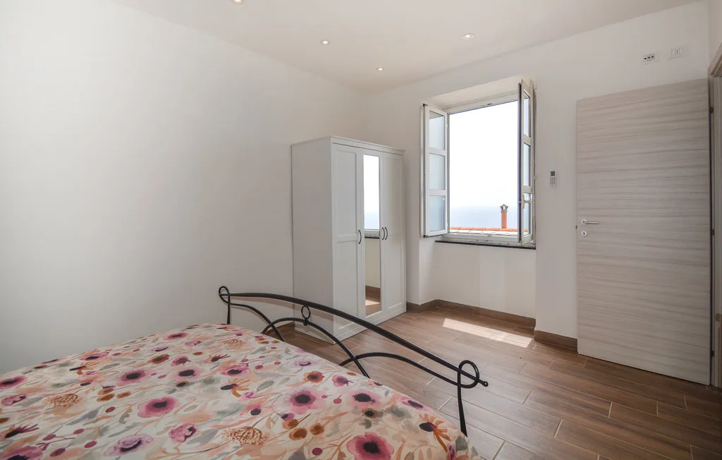 A bedroom with a bed, wardrobe, and open window.
