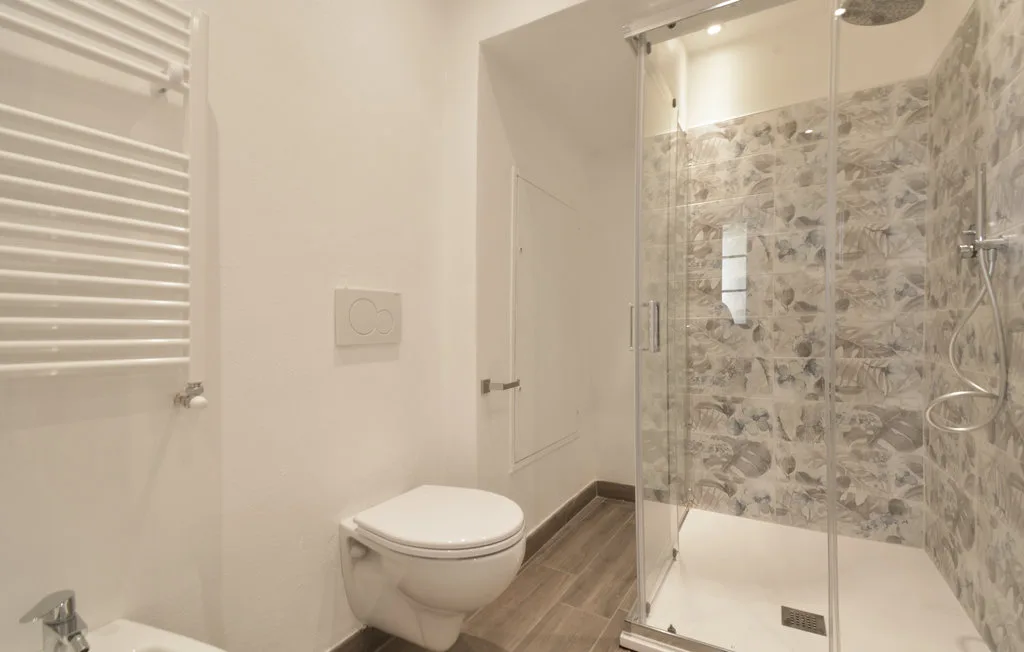 A bathroom with a toilet and glass-enclosed shower.