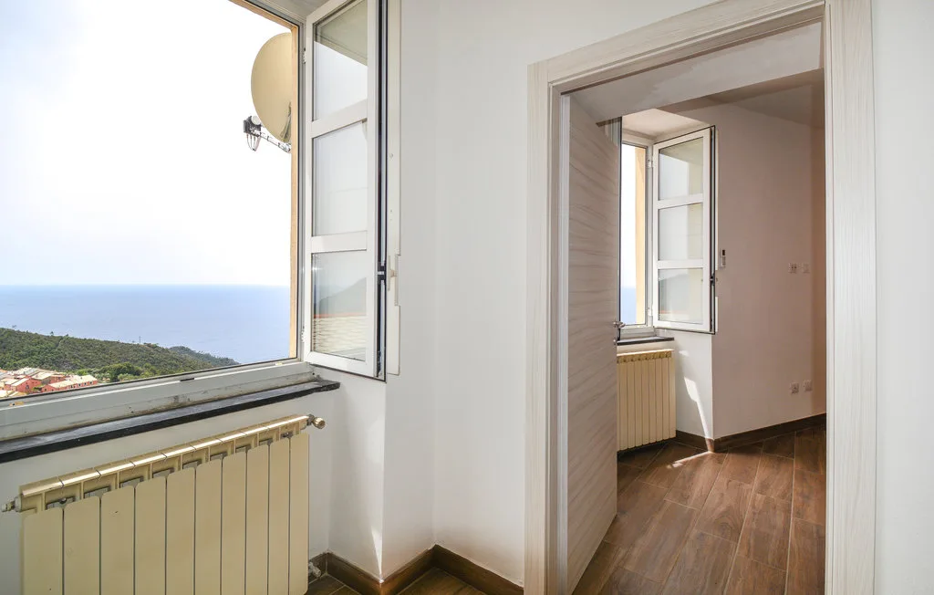 A bright room with an open window overlooking the sea.